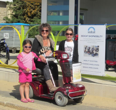 A lady on a scooter with two young people along side